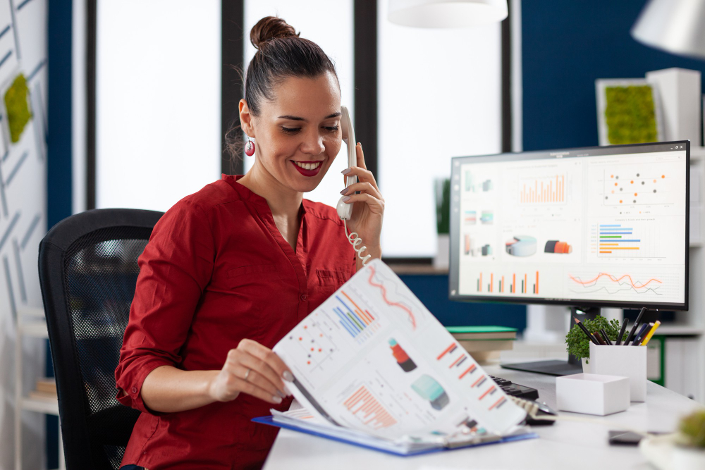 Femme au téléphone à son bureau pour de la prospection commerciale